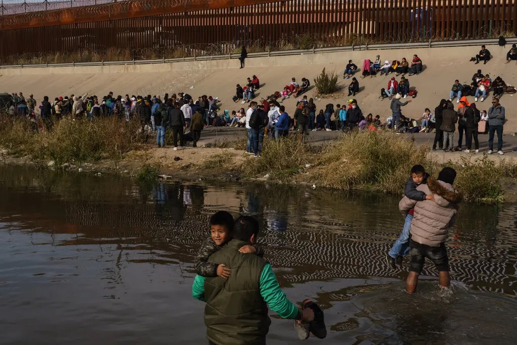 Men carrying children across the Rio Grande into El Paso, Texas last year.