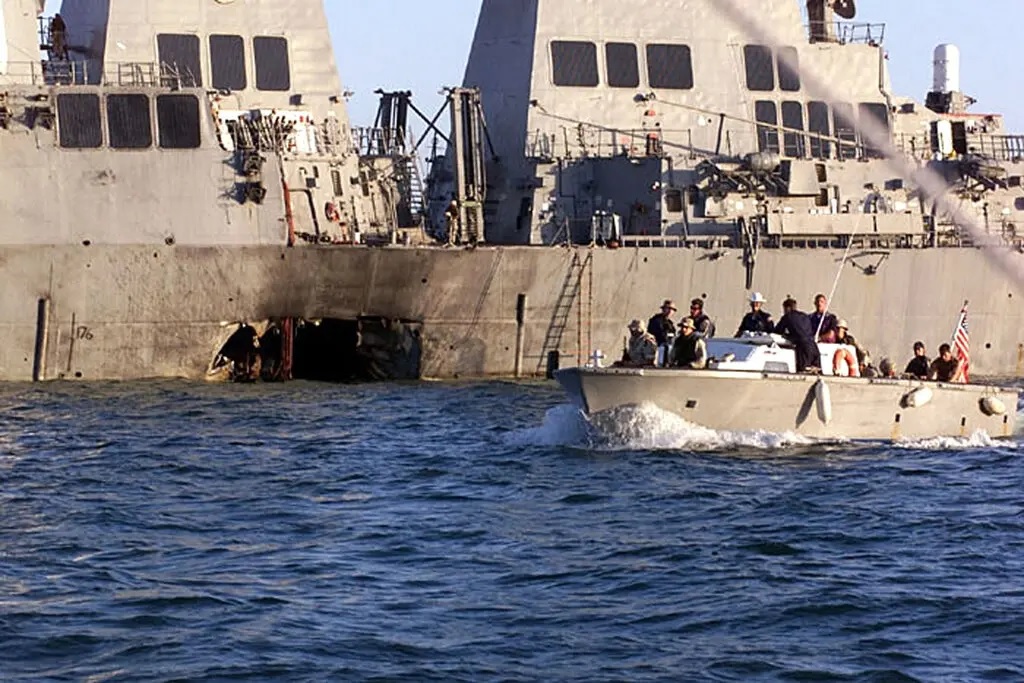 U.S. Navy and Marine Corps personnel in a small boat approach the damaged U.S.S. Cole in October 2000.