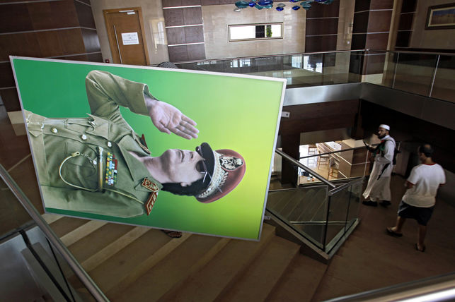Empleados de un hotel de Trpoli trasladan un retrato de Gadafi tras la cada de su Gobierno en agosto de 2011. 