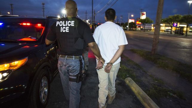 Un agente del ICE se lleva esposado a un detenido en una redada contra sin papeles.