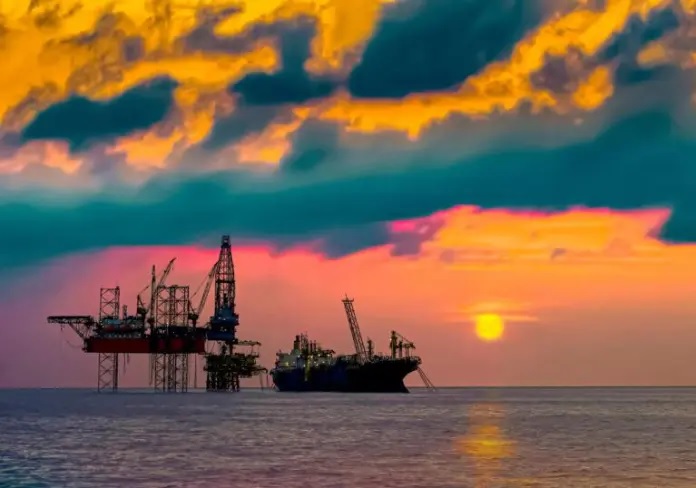 Un grupo de plataformas petrolferas en el agua durante la puesta de sol Descripcin generada automticamente con nivel de confianza bajo
