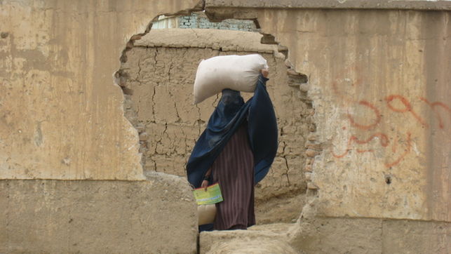 Una mujer camina llevando un saco en la cabeza en los barrios marginales de Mazar-e-Sharif, Afganistn, 23 de febrero de 2010  AI