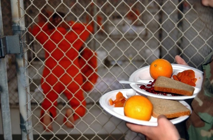 Los detenidos reciben comidas a base de arroz, porotos, zanahorias y naranjas en el Campamento X-Ray, Foto Suboficial de primera clase Shane T. McCoy/Marina de los EE. UU. vía The New York Times.