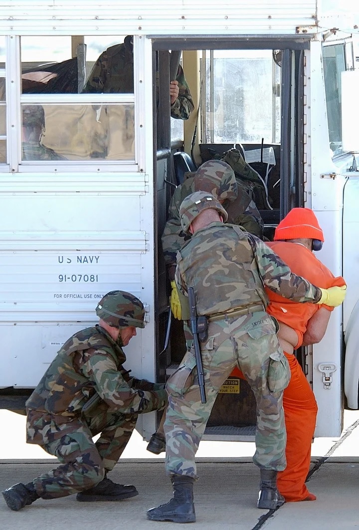 Marines cuestodiando de a dos a un prisionero. Foto Sargento de Estado Mayor Jeremy T. Lock vía The New York Times.