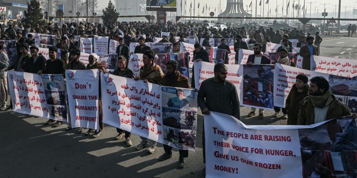 La gente sostiene pancartas antes de marchar por la calle durante una protesta en Kabul el 21 de diciembre de 2021, mientras el pas lucha contra una profunda crisis econmica. (Foto de Mohd RASFAN / AFP) (Foto de MOHD RASFAN/AFP a travs de Getty Images)