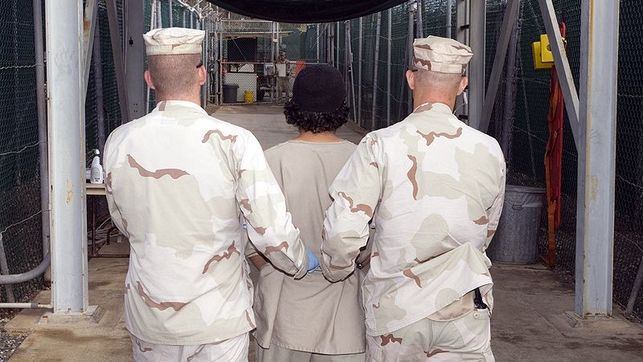 Dos soldados trasladan a un detenido en un campo de prisioneros de Guantánamo. Foto: Wikimedia